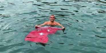 SOĞUK VE YAĞIŞLI HAVAYA ALDIRMADI, TÜRK BAYRAĞIYLA DENİZE GİRDİ